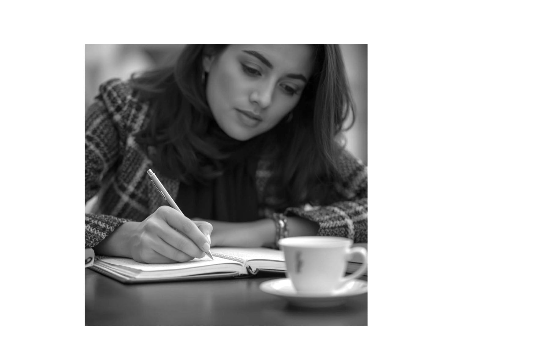 Woman writing in a notebook with a cup of coffee on a table